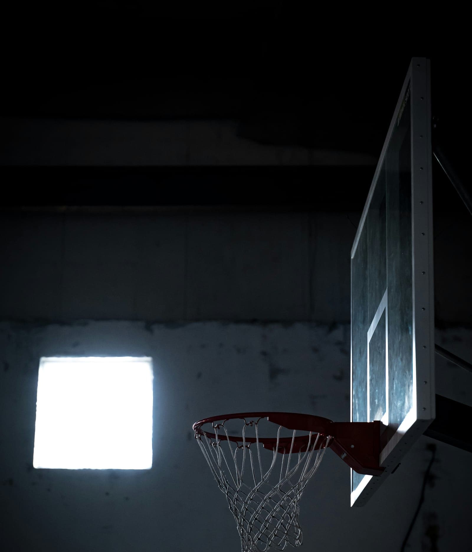 A basketball hoop and net against a dark gym wall